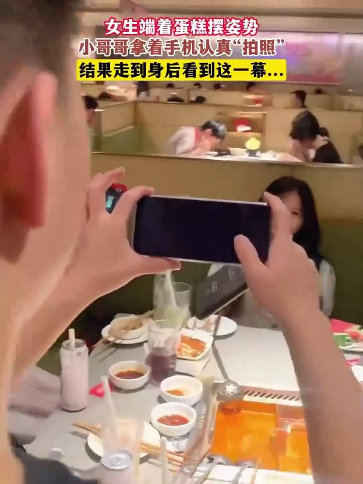 女生端着蛋糕摆姿势,小哥哥拿着手机认真“拍照”