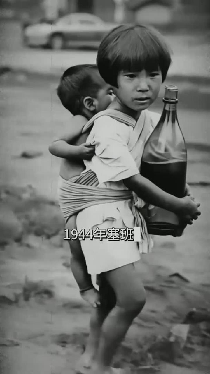 1944年塞班岛一个抱着水瓶的女孩背着弟弟
