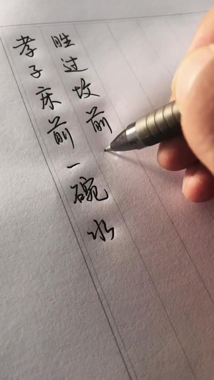 毛笔在贺年卡的烫金图案旁写字,金色与墨色交织,像把祝福镀了层光