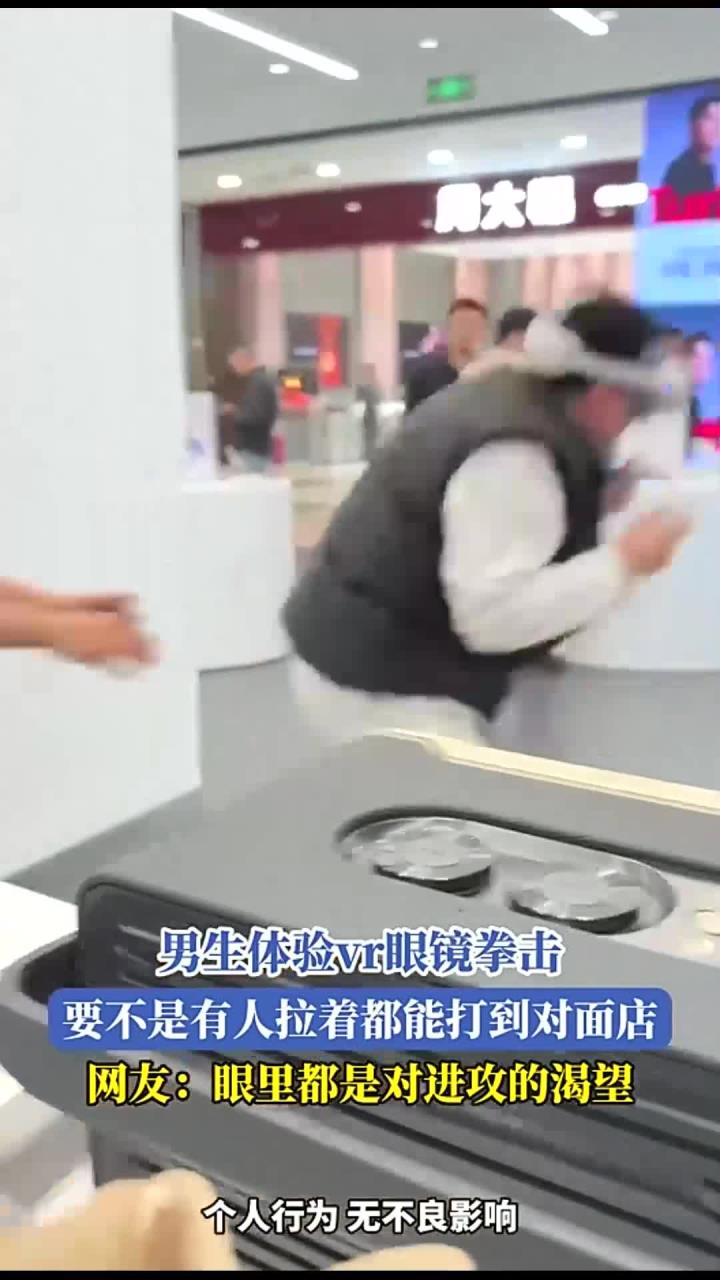 男生体验vr眼镜拳击,要不是有人拉着,都能打到对面店