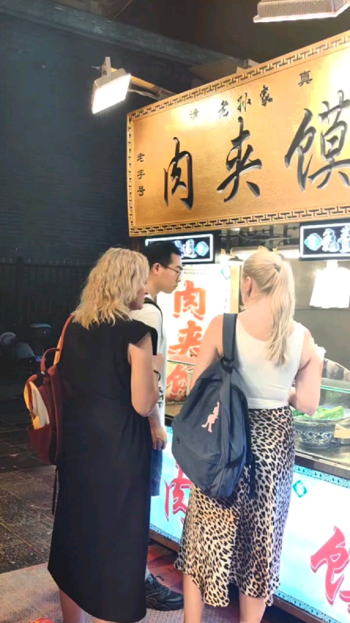 西安回民街,为一口老孙家肉夹馍,夜风中排起了长长队伍