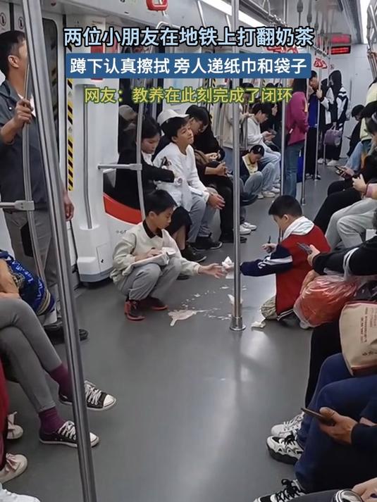 两位小朋友在地铁上打翻奶茶,蹲下认真擦拭 旁人递纸巾和袋子