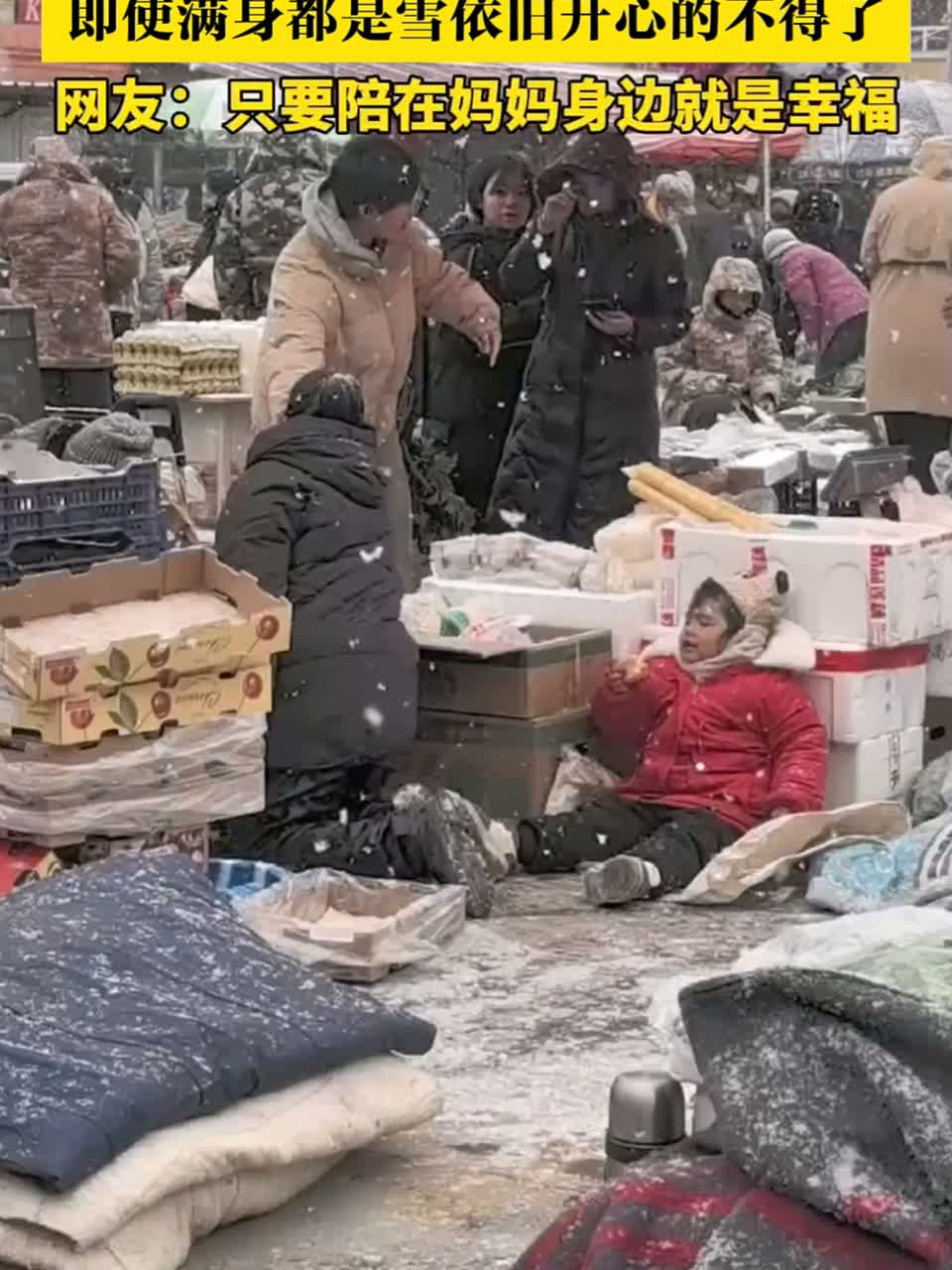 小朋友陪妈妈在雪地卖菜，即使满身都是雪依旧开心的不得了