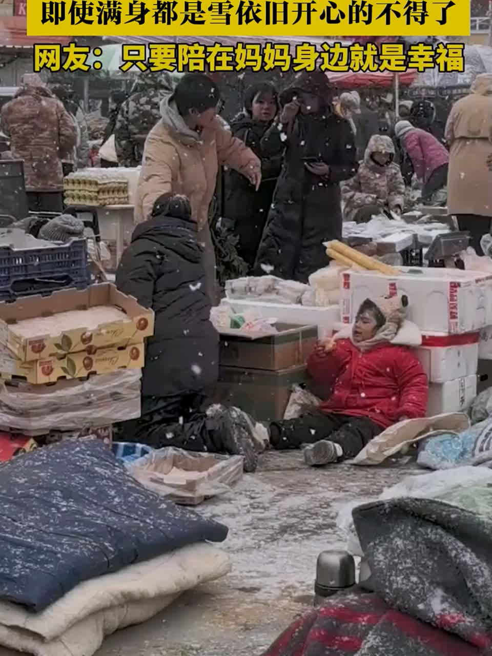 小朋友陪妈妈在雪地卖菜，即使满身都是雪依旧开心的不得了