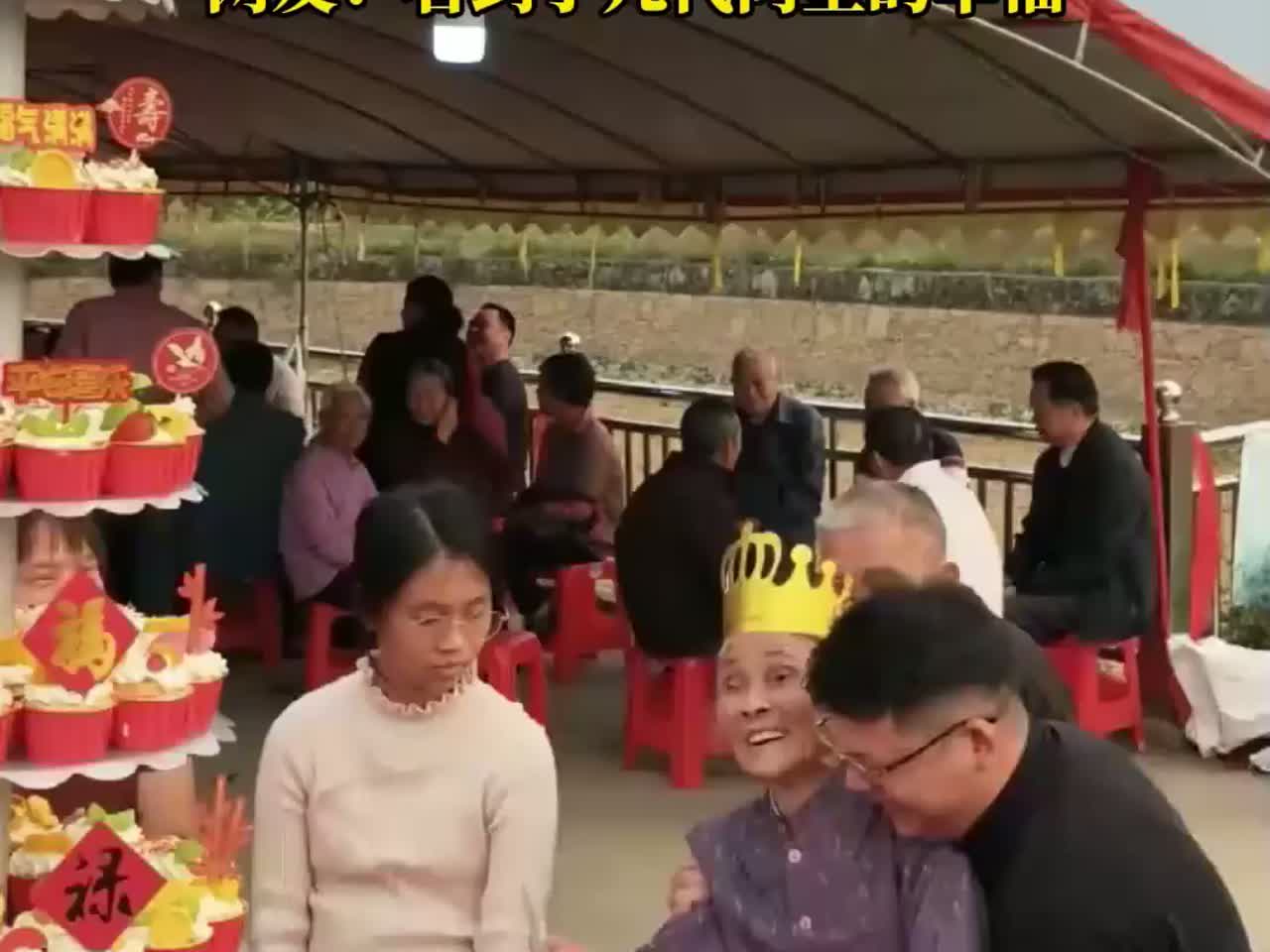 家人齐聚给90岁老人过寿,孙子抱着老人切九层蛋糕