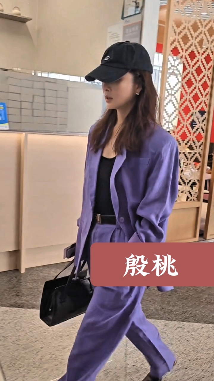 殷桃出行路透,头戴鸭舌帽,身穿紫色套装,单手插兜走路又美又酷