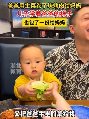 爸爸用生菜卷了块烤肉给妈妈,儿子学着爸爸的样子也包了一份给妈妈 父母是孩子最好的老师 儿子