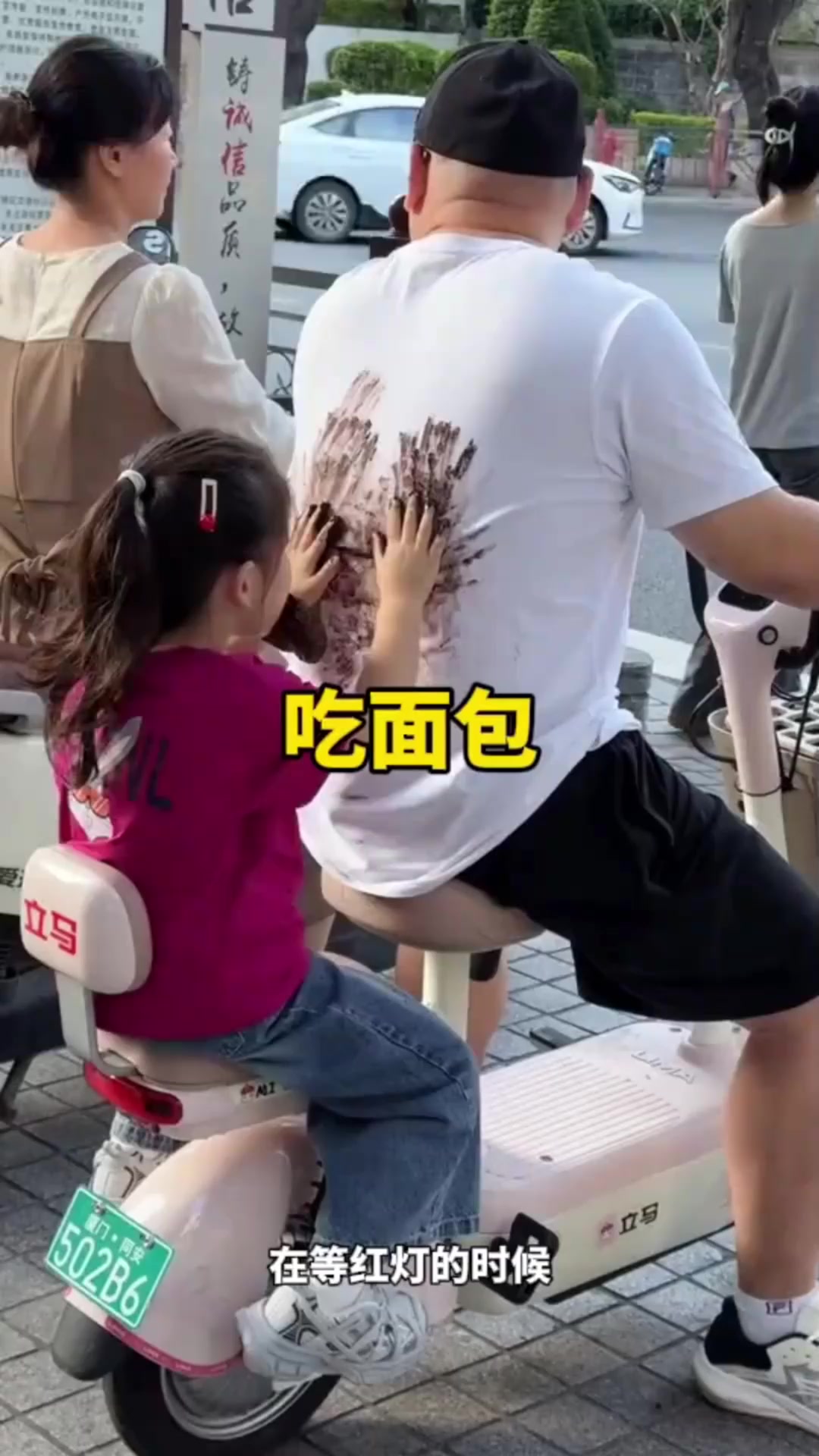 小女孩坐在车子后面吃面包