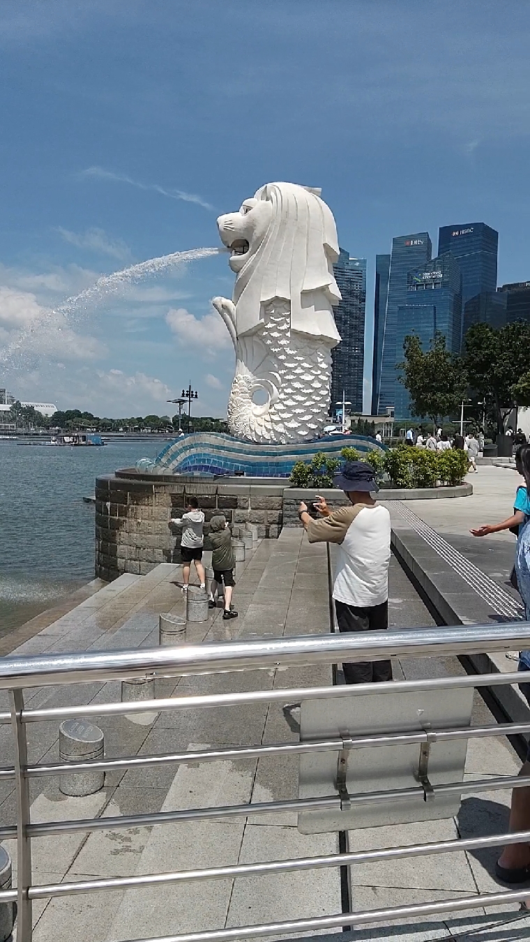 蓝天白云下的白色狮头鱼身塑像。