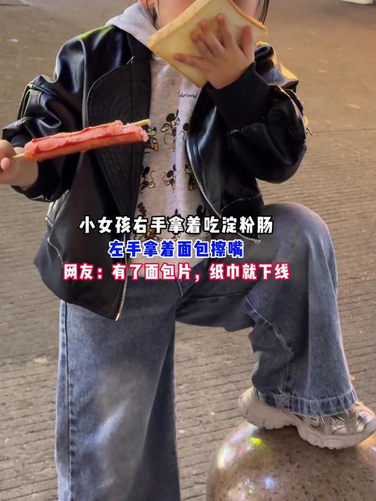 小女孩右手拿着吃淀粉肠,左手拿着面包擦嘴