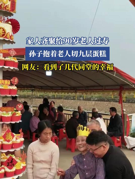 家人齐聚给90岁老人过寿，孙子抱着老人切九层蛋糕