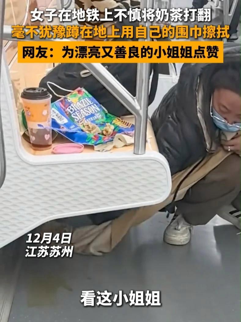 12月4日，江苏苏州，女子在地铁上不慎将奶茶打翻，毫不犹豫蹲在地上用自己的围巾擦拭。网友：