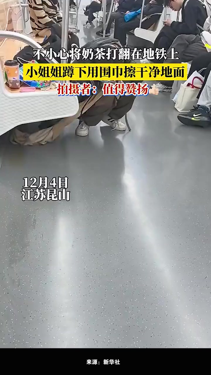 小姐姐不小心将奶茶打翻在地铁上后，蹲下身用自己的围巾擦干净地面