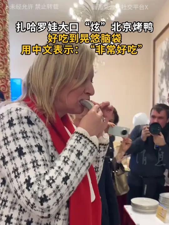 扎哈罗娃大口“炫”北京烤鸭 好吃到晃悠脑袋 用中文表示：“非常好吃”