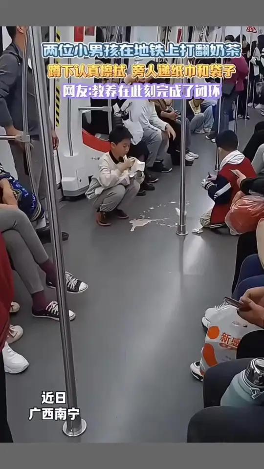 近日,广西南宁两位小男孩在地铁上打翻奶茶,蹲下认真擦拭旁人递纸巾和袋子。网友:教养在此刻完