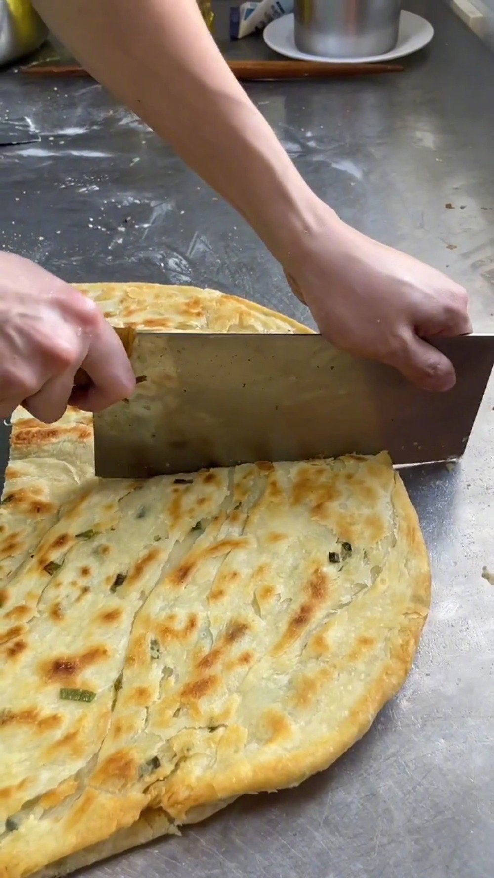 「申请加入葱油饼界天花板」把松软的面团擀成薄饼状,抹上一层油后撒上切好的翠绿葱花,卷成卷揉