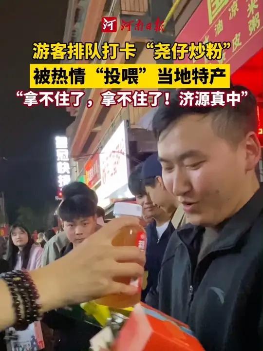 10月6日晚,河南济源。游客排队打卡“尧仔炒粉”,被工作人员热情“投喂”当地特产,直呼“拿