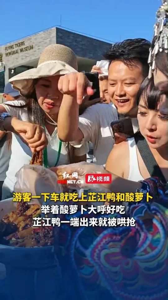7月29日,湖南怀化,游客一下车就吃上芷江鸭和酸萝卜,举着酸萝卜大呼好吃,芷江鸭一端出来就