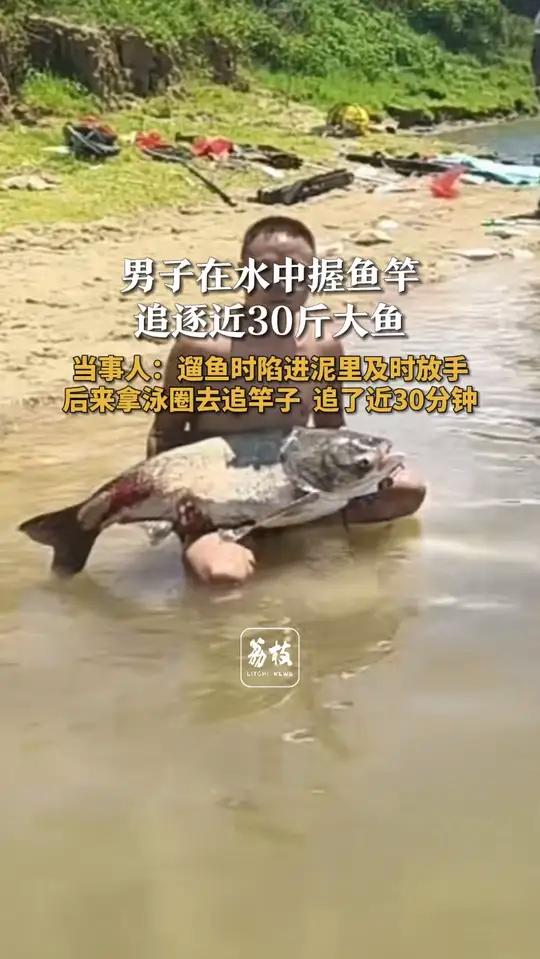 男子在水中握鱼竿追逐近30斤大鱼 当事人：遛鱼时陷进泥里及时放手 后来拿泳圈去追竿子 追了