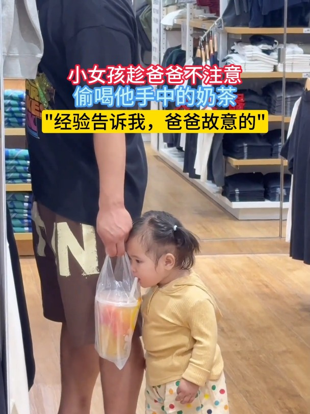 小女孩趁爸爸不注意,偷喝他手中的奶茶
