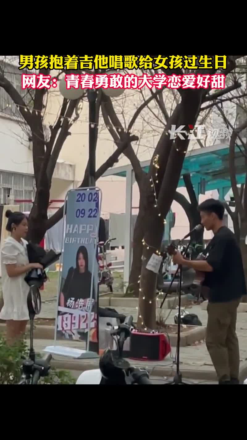 22日,武汉一高校里,男孩抱着吉他、准备好易拉宝给女孩唱歌庆生,学生时代的这份纯粹大概是女