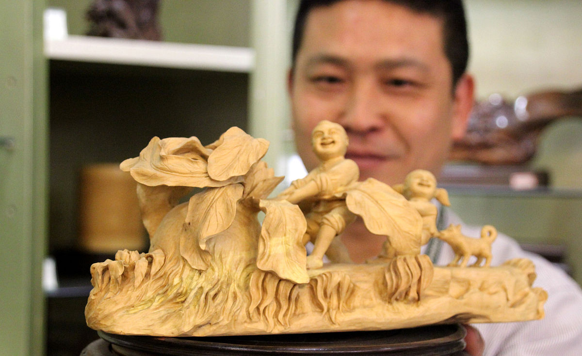 2017年4月15日,江苏苏州,工作人员在红木家具文化博览会上展示木雕工