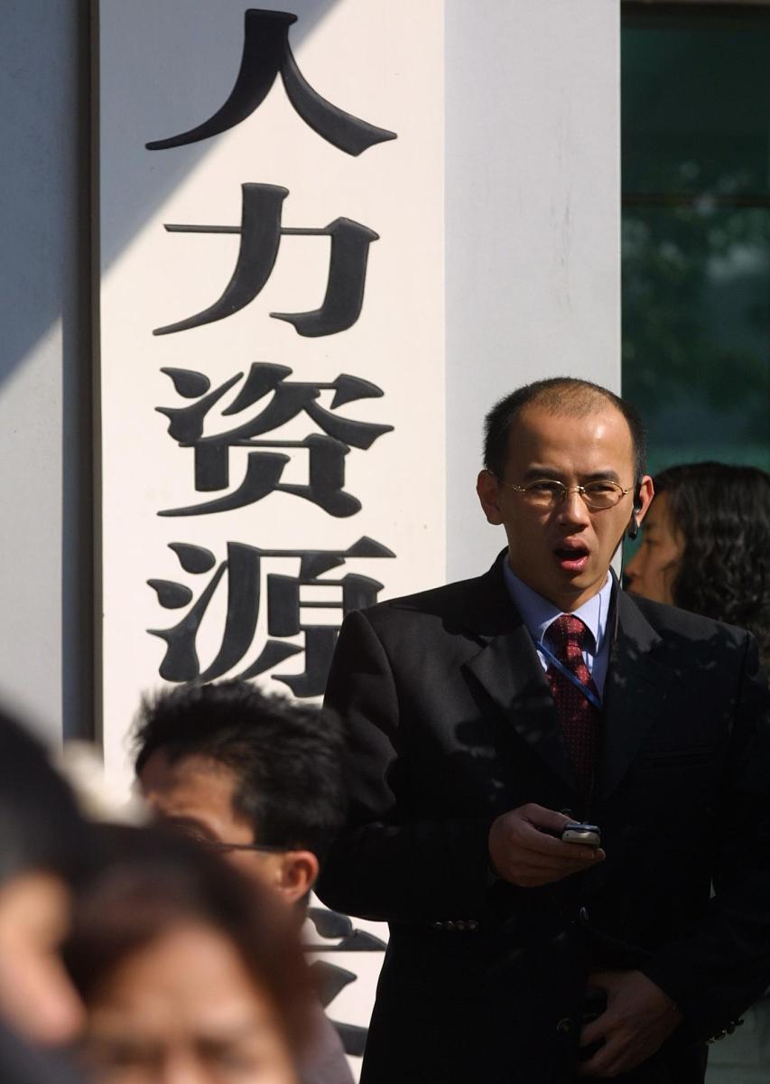一名应聘着在"人力资源开发"牌子前打电话.2004年2月13日,海南省就业