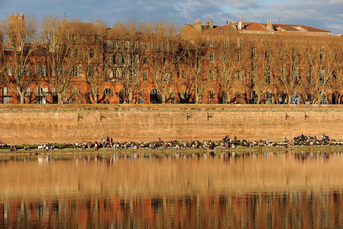 people enjoy the spring sunshine on a bank of the garonne in tou