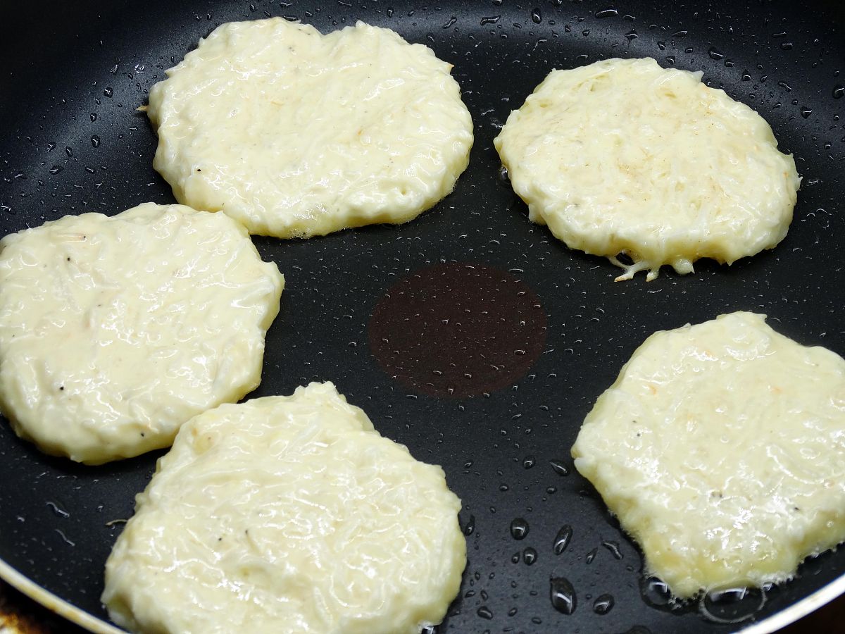 图为香煎白萝卜饼的制作过程 锅内加入少许色拉油,将萝卜丝糊分成均匀