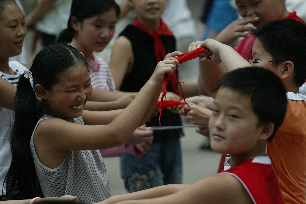 2007年9月12日,郑州,在跳校园集体舞的时候,一名小女孩很害羞,用红领