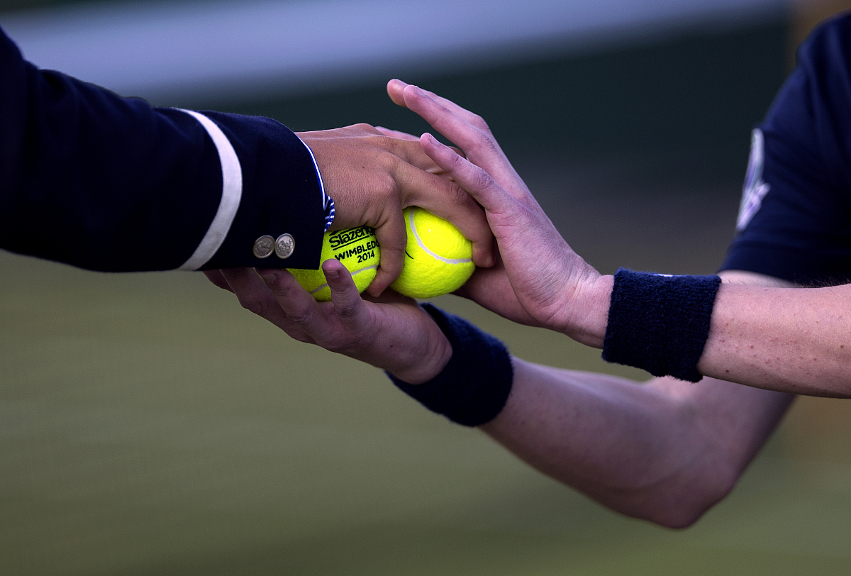 a line judge passes some balls to a ball boy