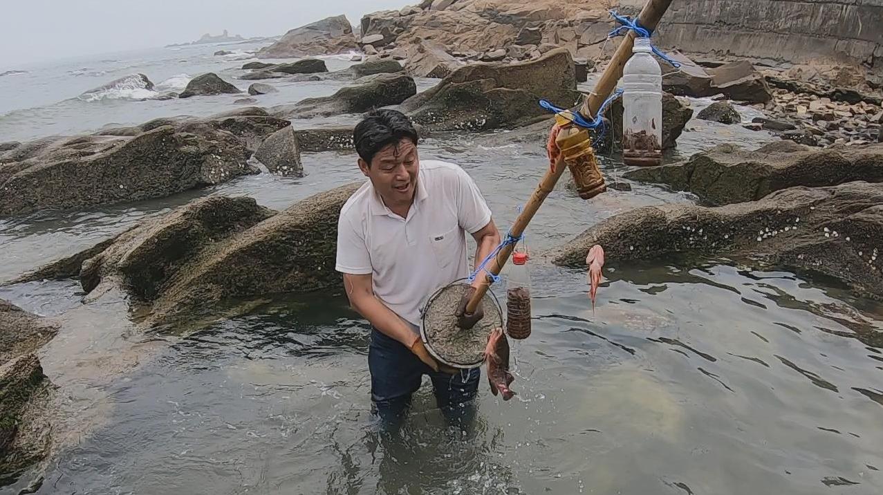 阿阳在竹竿上挂上鱼钩诱饵,扔到海边水坑中,收获一条值钱鱼