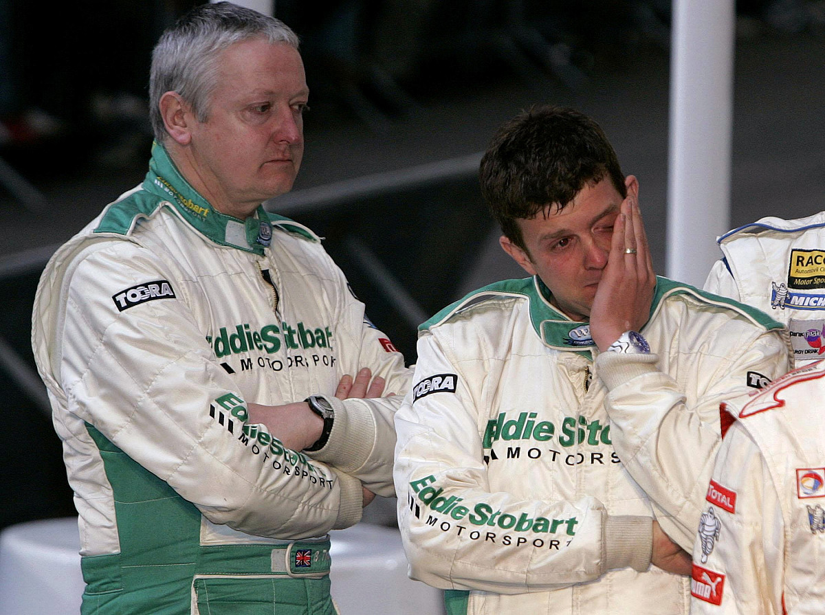 rally driver mark higgins (r) wipes way a tear watched by his co