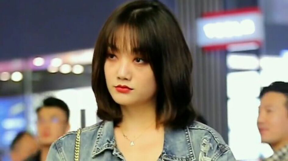 美女手拿着奶茶在街上摆拍,宽松的牛仔衣搭配裙子非常好看