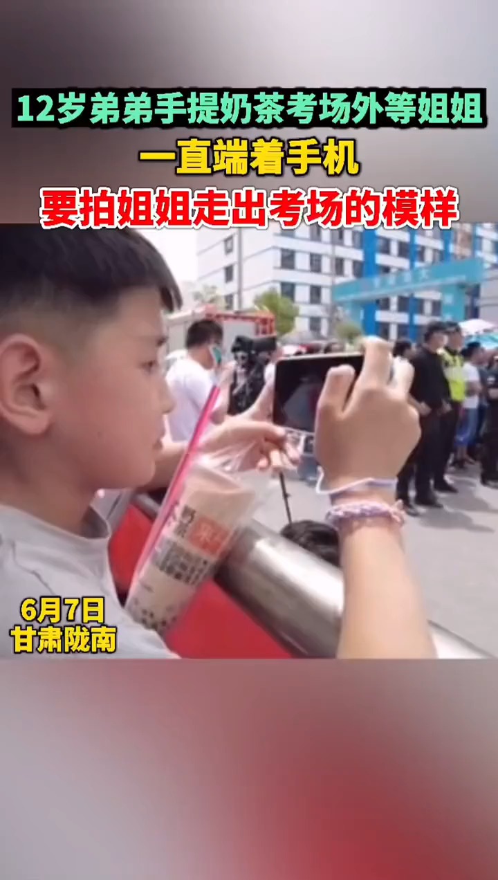 弟弟手提奶茶考场外等参加高考的姐姐,始终端着手机要记录姐姐走出考场的模样。