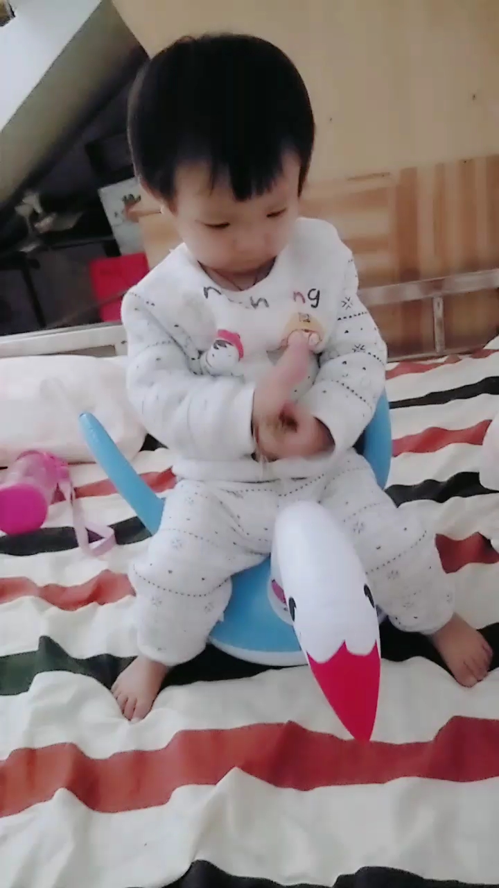 宝宝拿鸭子坐在床上。