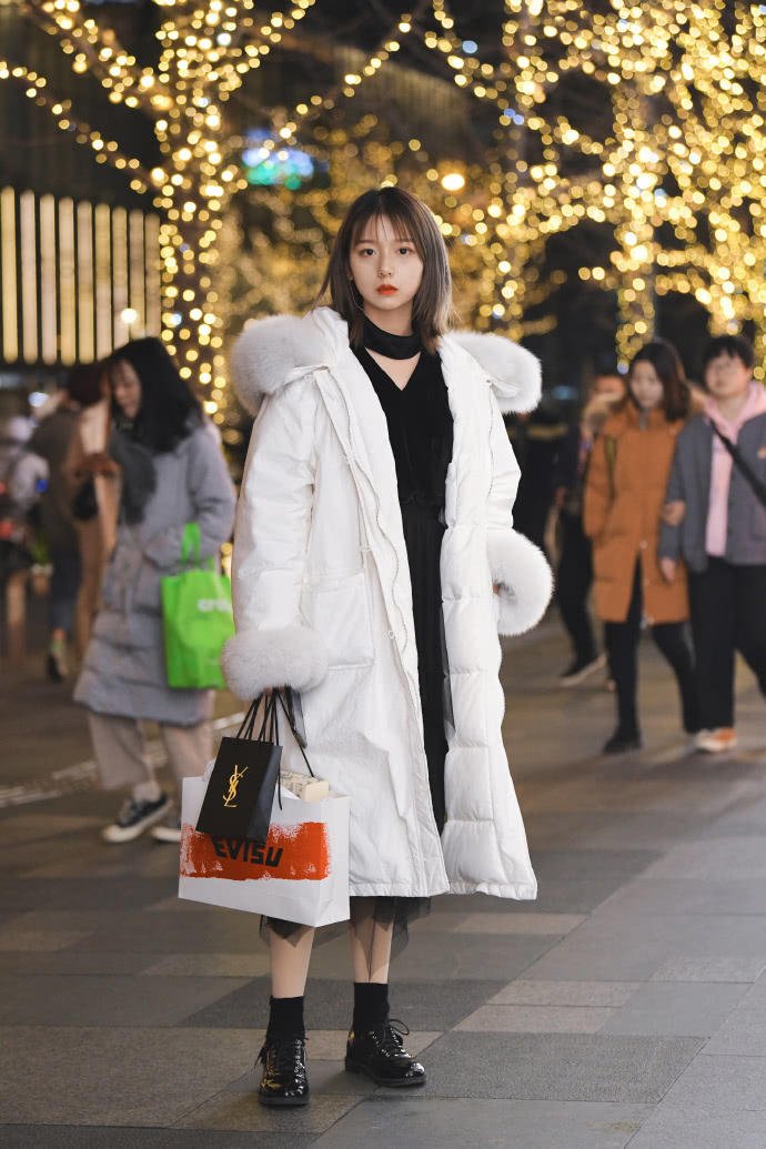 短发小姐姐穿着一身长款的白色羽绒服,搭配着毛茸茸的帽子元素,黑色的
