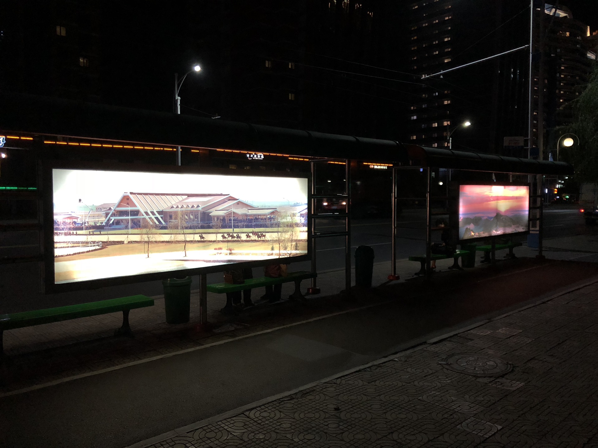 图为平壤夜间的公交站牌,上面没有商业广告牌,都是一些朝鲜的风景画面