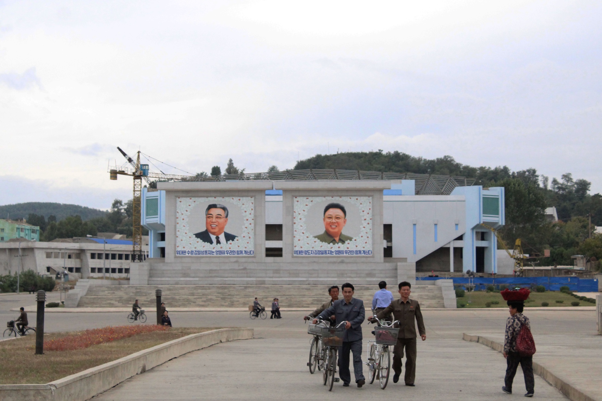 图为朝鲜罗先,几名朝鲜男人推着自行车走在路上.