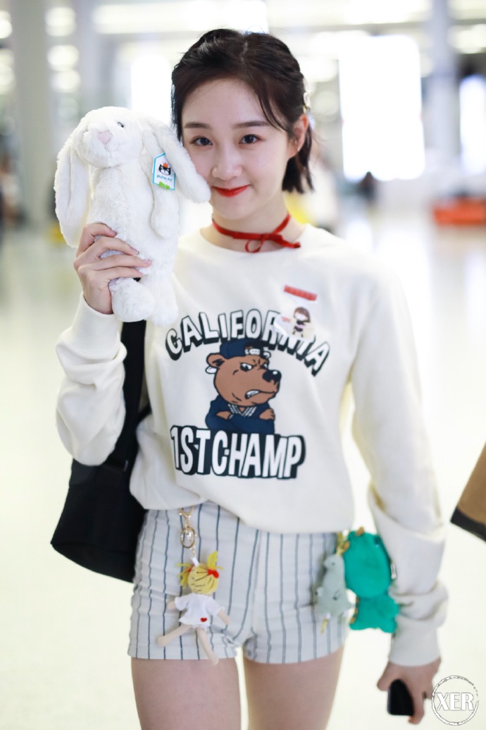 李子璇穿白色卫衣搭配白色条纹短裤现身,手里拿着白