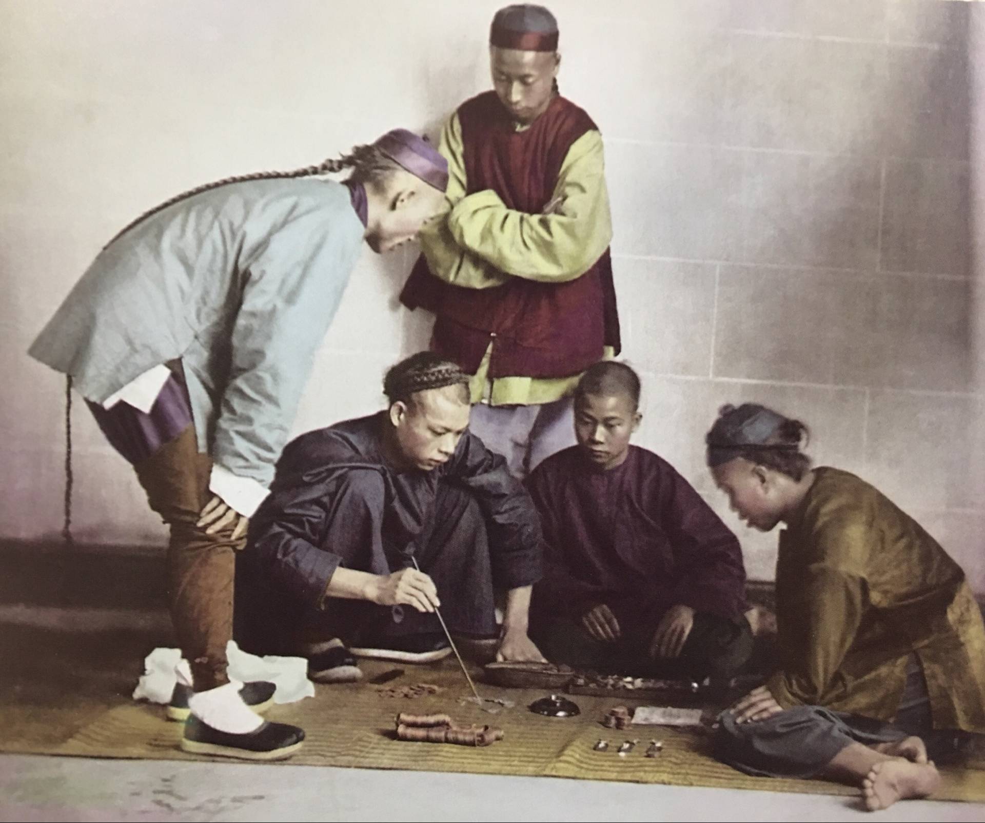 清朝末年赌博盛行,在街头经常有人在赌博,可以看到图片上有赌注,就是