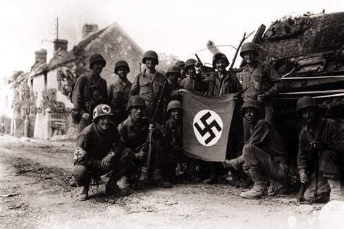 图为二战时期,美军士兵缴获纳粹军旗