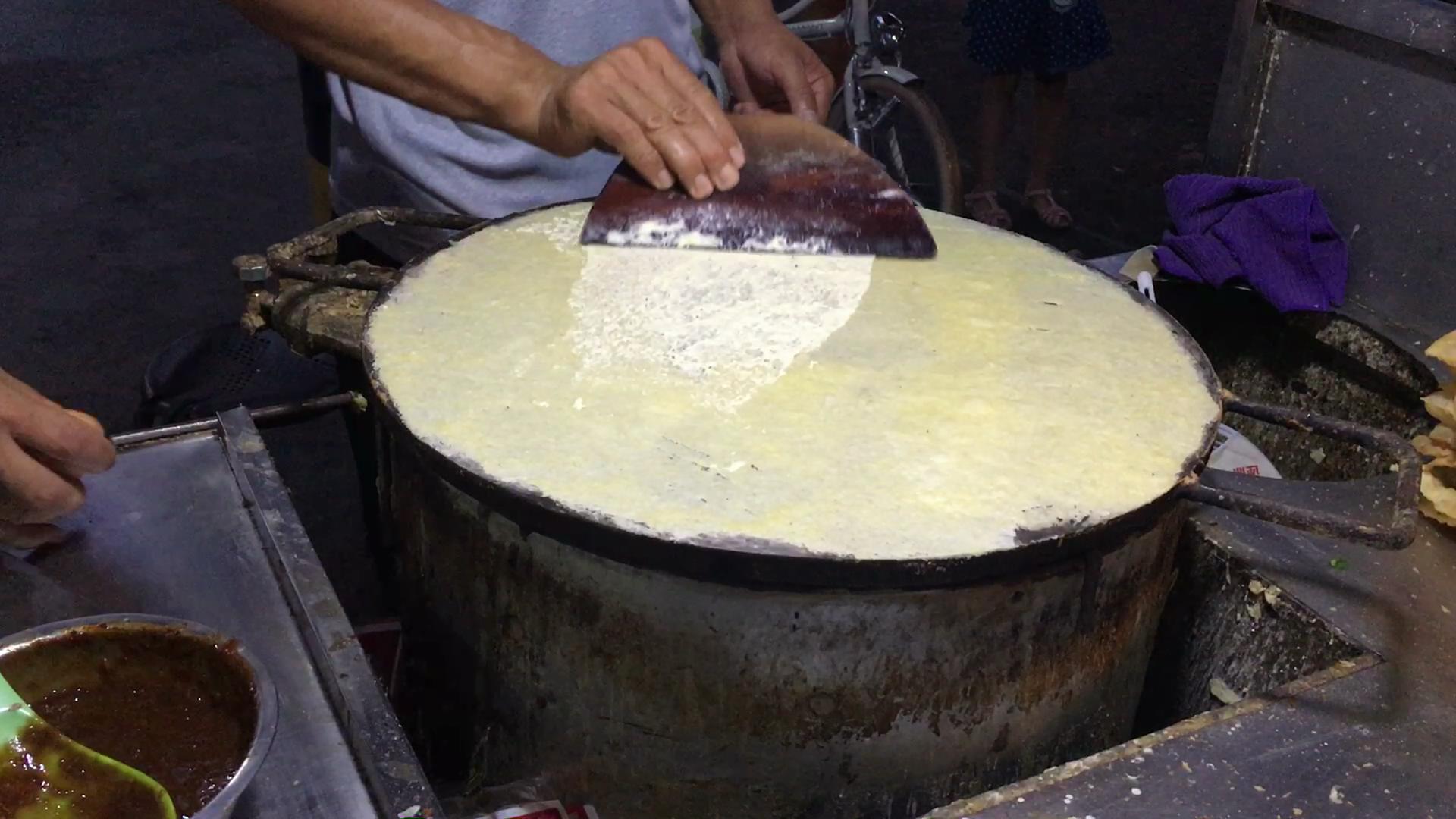 第20秒,打上的一个鸡蛋,已经在饼上摊开,这时的煎饼已经有七八分成熟