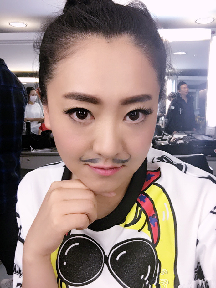 月亮姐姐在化妆间给自己涂粉底,并露出了满意的笑容.