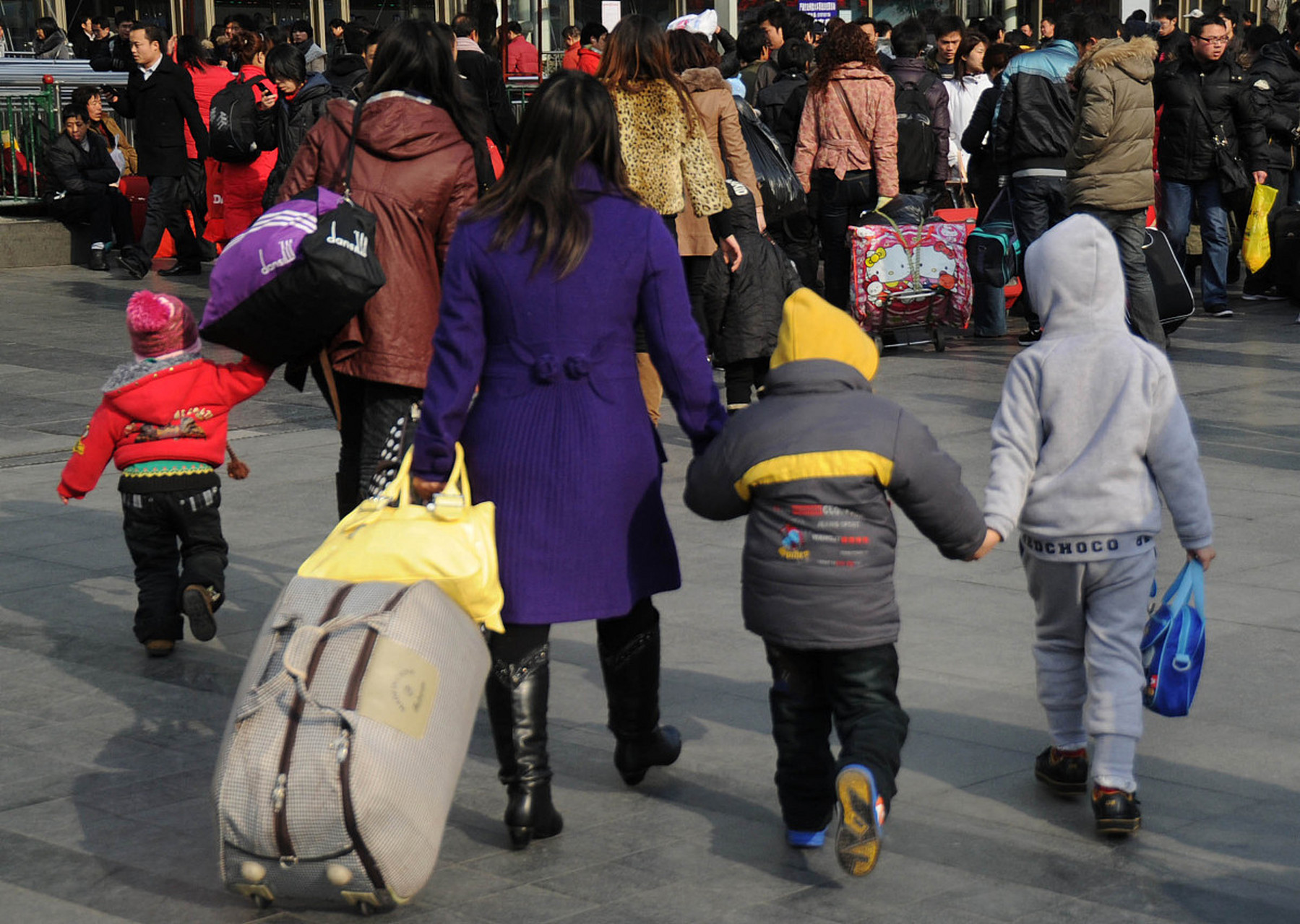 人们拖着行李箱,扛着大包小包,脸上洋溢着喜庆的笑容,三三两两地走在