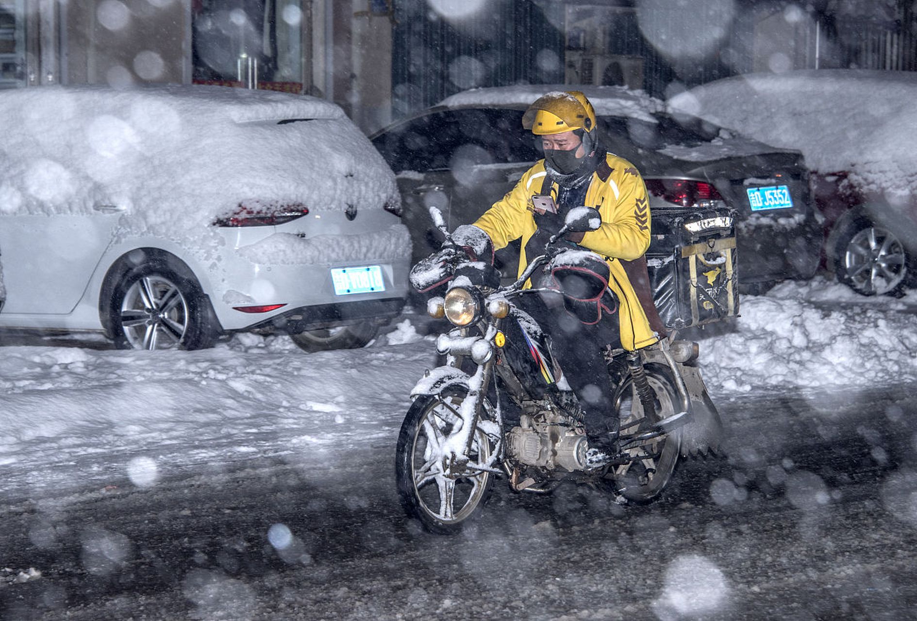 暴雪后,城市被雪覆盖,道路滑,一位外卖小哥在送餐途中听到小车打滑,他