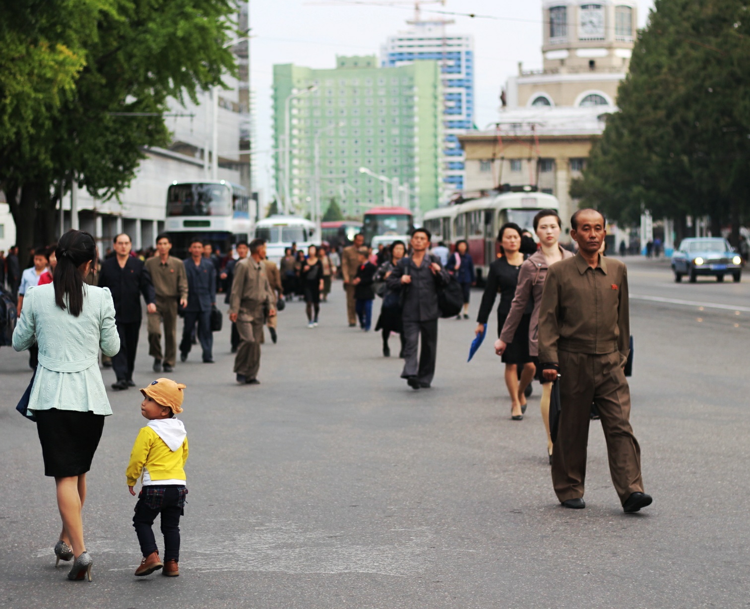 圖為朝鮮平壤街景,一名老人推著獨輪車走在路上,遠處的建築是柳京飯店