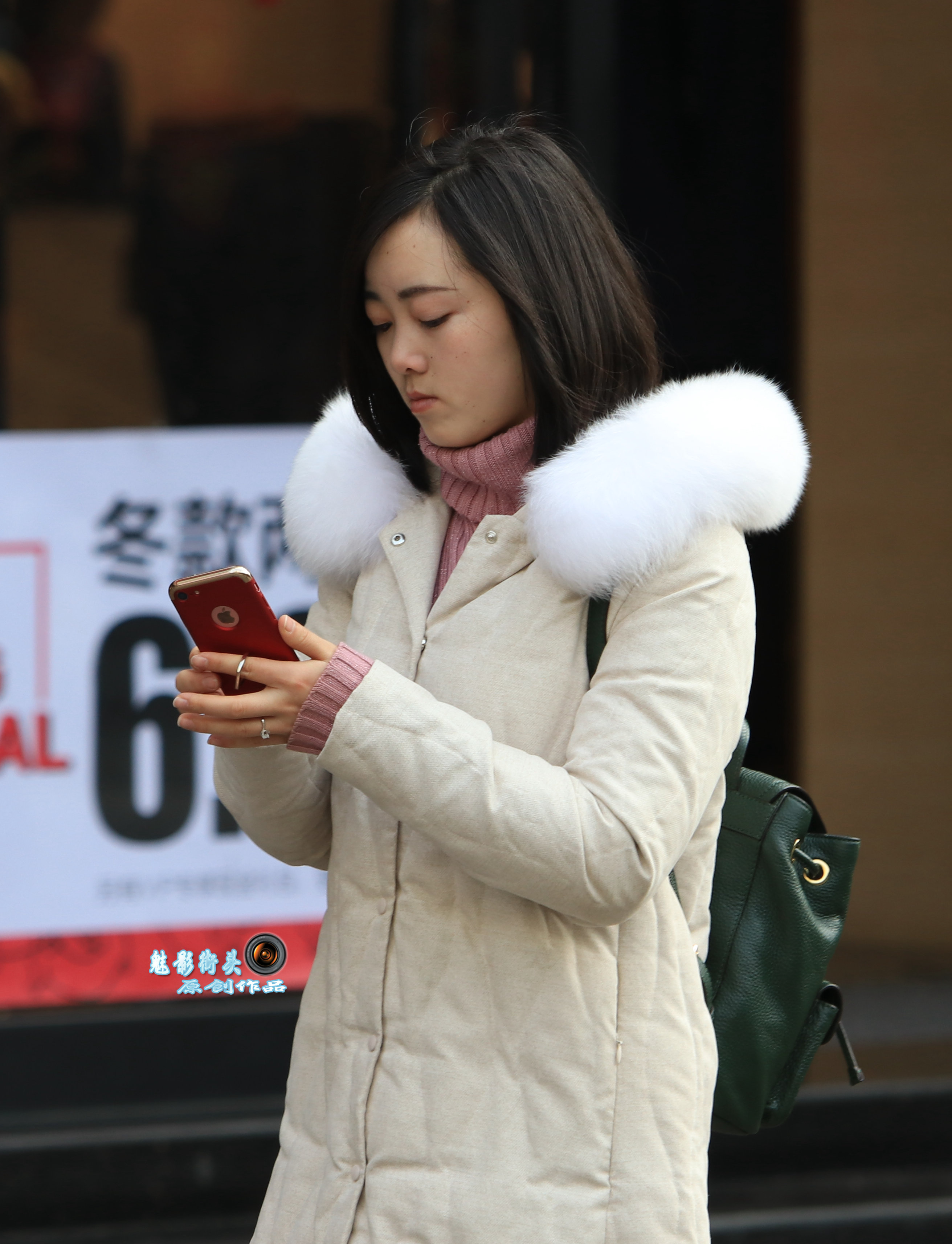穿白色羽绒服的美女玩着手机漫步街头,不施脂粉依然眉清目秀