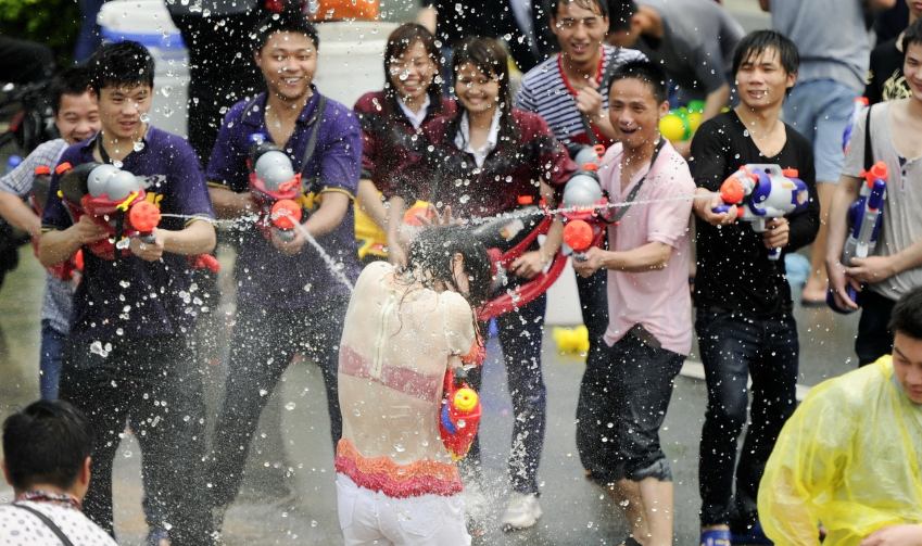 图为两名女子被众多男生围在当中射水,全身衣衫湿透