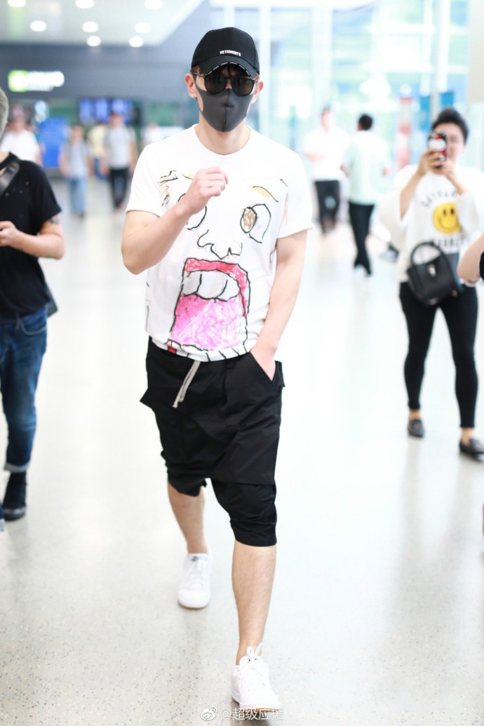 邓伦白色t恤搭配黑色短裤现身机场遮捂严实,衣服上的图案是亮点